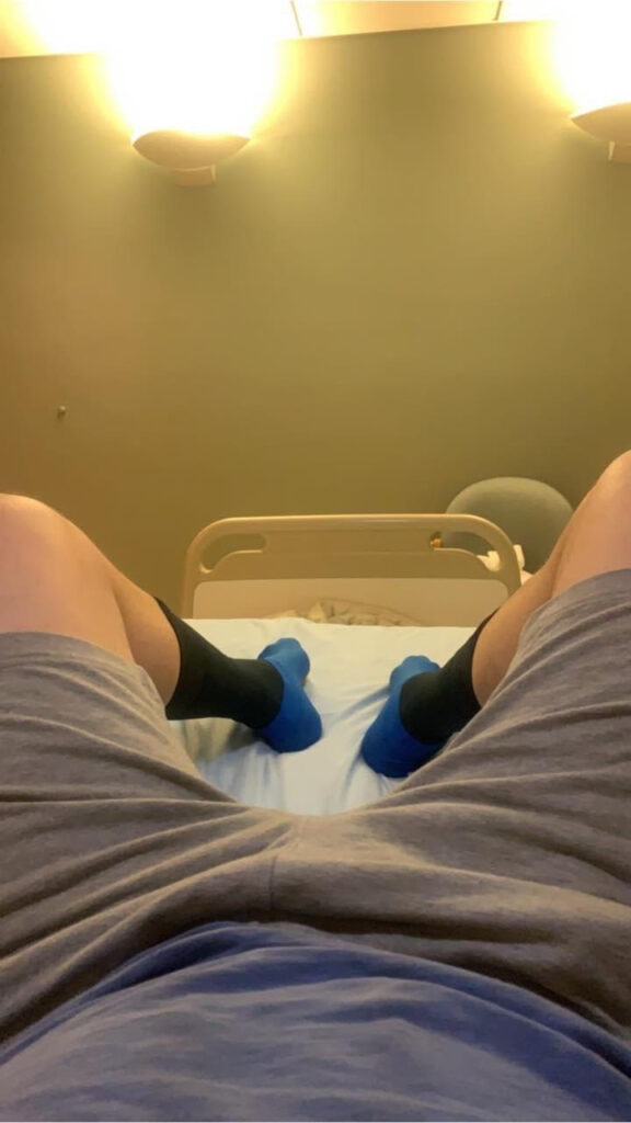 Sat on a hospital bed after penile cancer surgery, eating raspberry cheesecake. St Anthony's hospital, Surrey, England